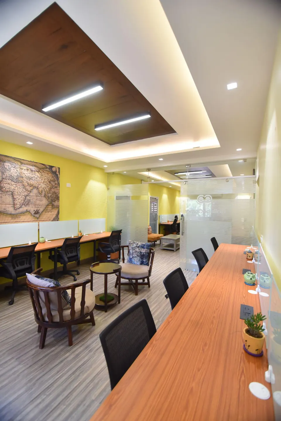 A row of dedicated desks in the bright lounge at CollaboCorner, Jaipur